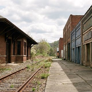 Weathered brick commercial building beside railroad tracks at the bottom of a river gorge